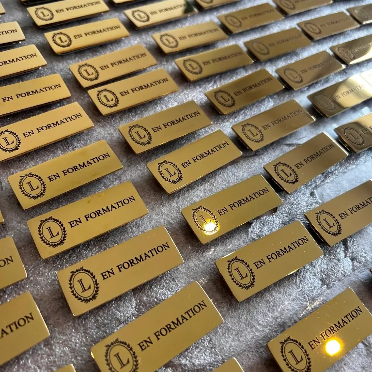 Série de badges nominatifs en laiton poli miroir gravés au laser avec logo et mention "En formation"