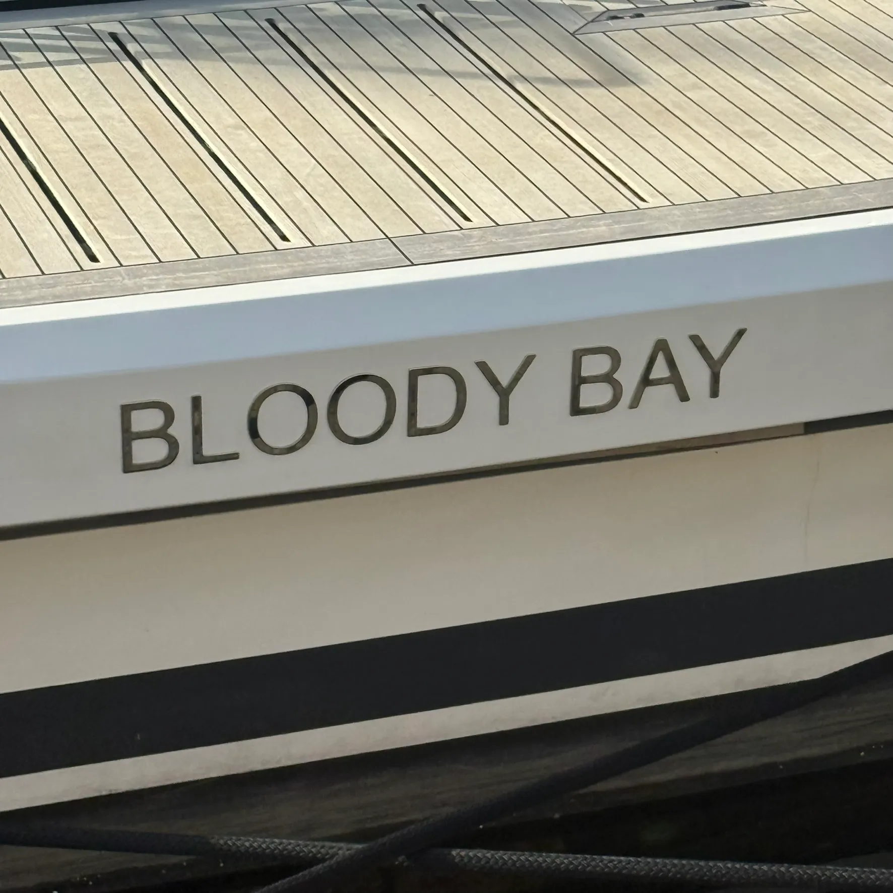 Enseigne de bateau « Bloody Bay » en lettres découpées inox poli fixées sur le tableau arrière au-dessus de la plage de bain
