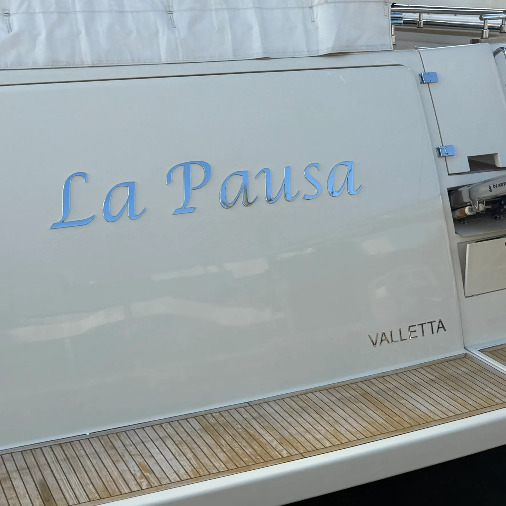 Enseigne de bateau « La Pausa » en lettres script inox poli fixées sur la coque blanche d'un yacht immatriculé à Valletta