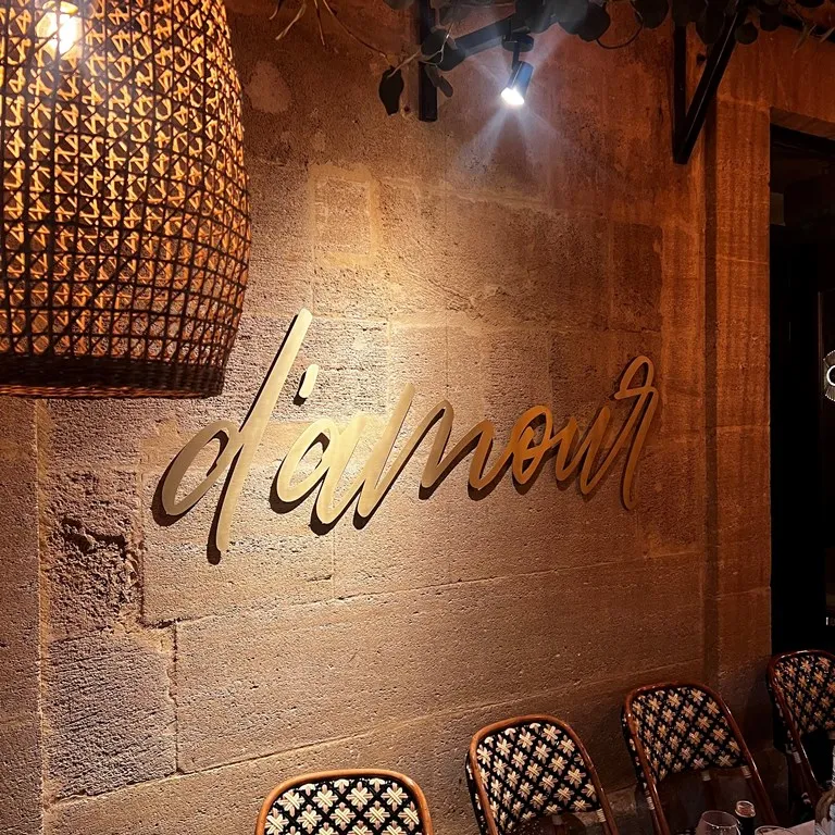 Enseigne murale « d'amour » en lettres script laiton doré fixées sur un mur en pierre dans une salle de restaurant