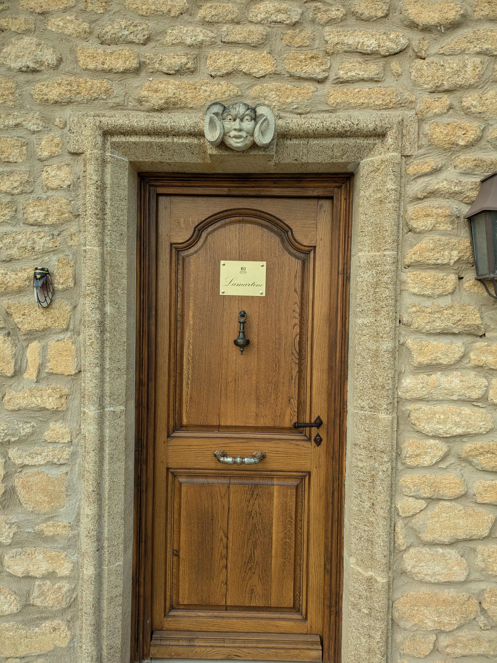 Plaque de maison en laiton gravée d'un nom, vissée sur une porte en bois massif d'une façade en pierre